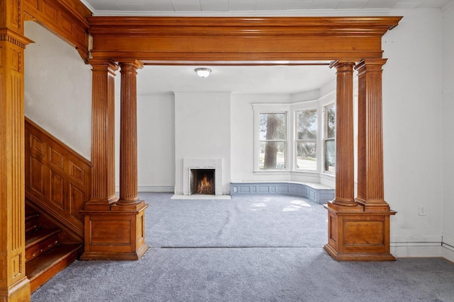 unfurnished living room featuring ornate columns, carpet flooring, crown molding, and a high end fireplace