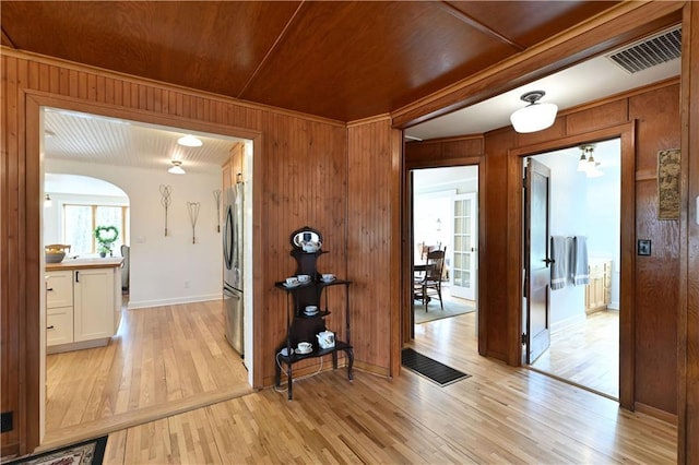 13195 Kavanaugh Rd, Cable, WI 54821 - corridor with visible vents, baseboards, wooden walls, arched walkways, and light wood-style flooring