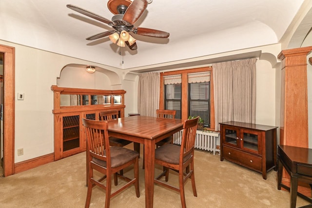 dining area with ceiling fan, light colored carpet, baseboards, and radiator