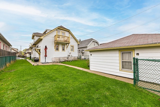 back of house with a yard, fence, and a balcony