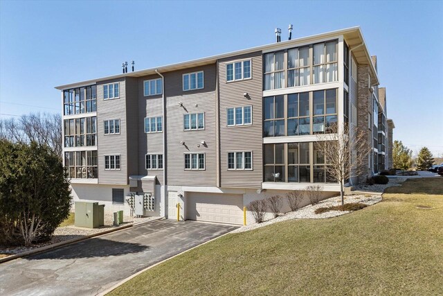 view of property featuring a garage, aphalt driveway, and central AC