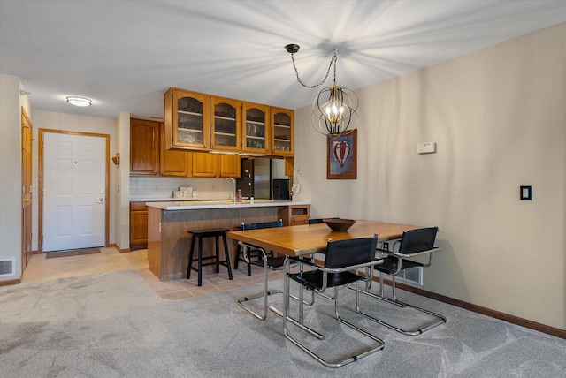dining room with a notable chandelier, light colored carpet, baseboards, light tile patterned floors, and visible vents
