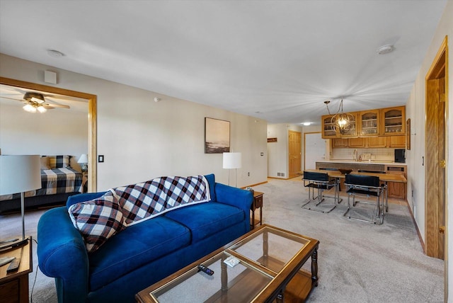 living room with baseboards, light colored carpet, and ceiling fan