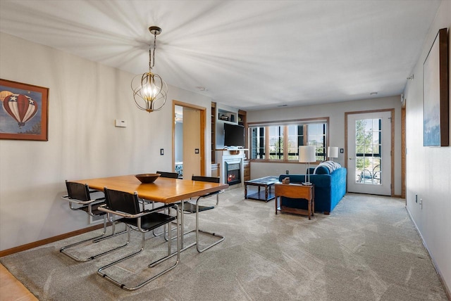 carpeted dining room with baseboards and a lit fireplace