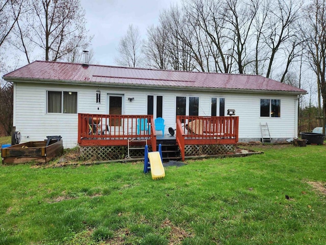 rear view of house with a lawn, a wooden deck, and metal roof