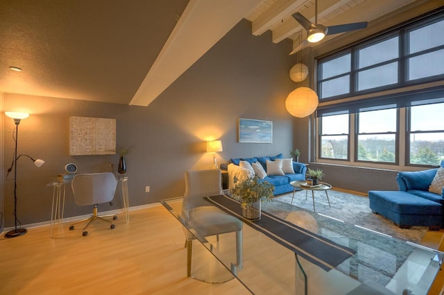 living room with ceiling fan, baseboards, vaulted ceiling with beams, and wood finished floors