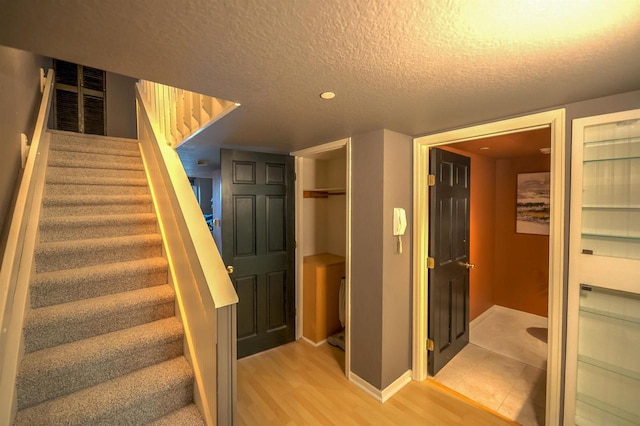 stairs featuring baseboards, a textured ceiling, and wood finished floors