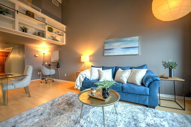 living room with baseboards, visible vents, and wood finished floors
