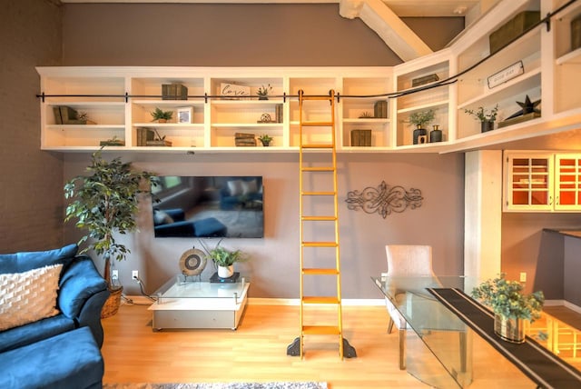 living area with lofted ceiling with beams and wood finished floors