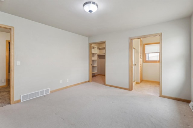 unfurnished bedroom featuring visible vents, baseboards, carpet floors, and a spacious closet