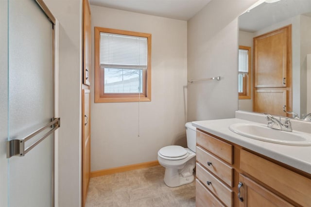 bathroom with toilet, baseboards, a shower with shower door, and vanity