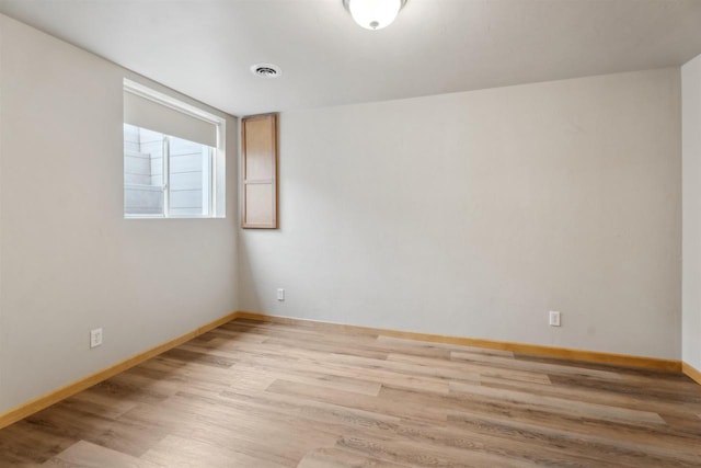 empty room with baseboards, visible vents, and light wood finished floors