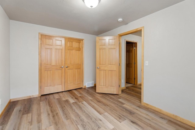 unfurnished bedroom with baseboards, a closet, light wood-style flooring, and visible vents