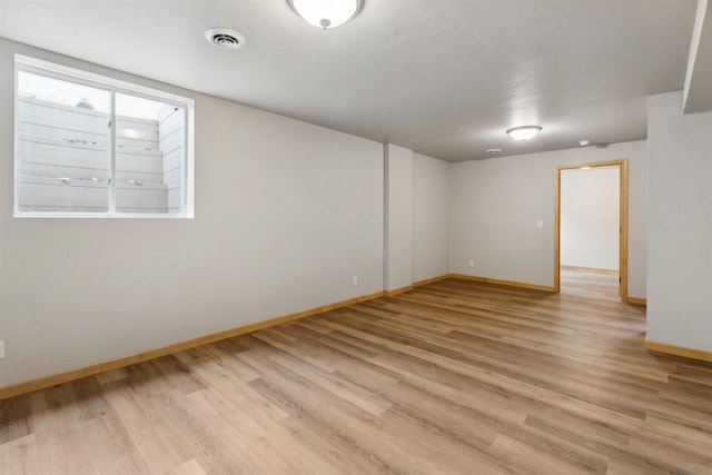 empty room featuring baseboards, light wood finished floors, and visible vents