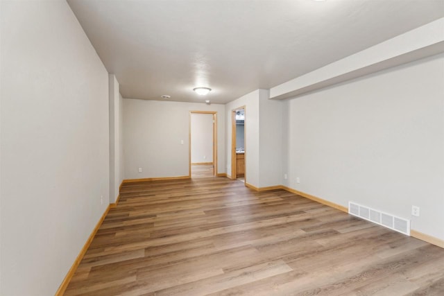 unfurnished room featuring baseboards, visible vents, and light wood-style floors