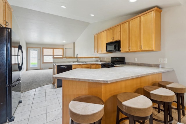 kitchen featuring a peninsula, light colored carpet, light countertops, black appliances, and vaulted ceiling