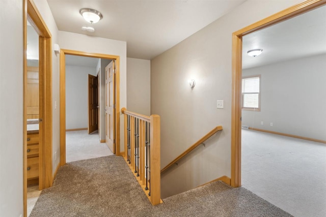 corridor featuring carpet floors, baseboards, and an upstairs landing