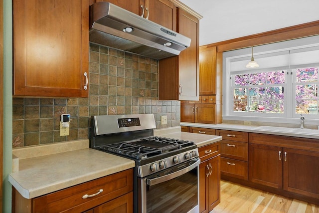 126 S Hancock St, Madison, WI 53703 - kitchen featuring stainless steel gas range, under cabinet range hood, brown cabinets, a sink, and light countertops