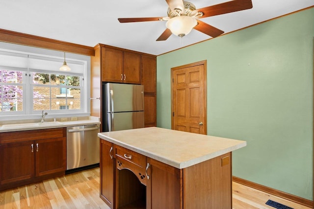 126 S Hancock St, Madison, WI 53703 - kitchen with appliances with stainless steel finishes, light wood-style flooring, a sink, brown cabinetry, and light countertops