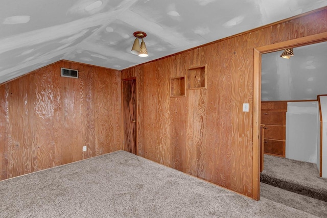 unfurnished room featuring wooden walls, carpet, and visible vents