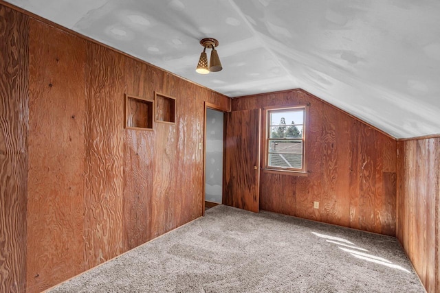additional living space featuring carpet floors, wood walls, and lofted ceiling