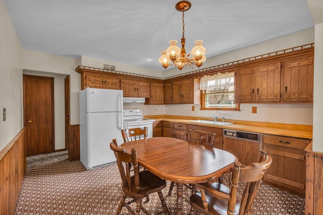 kitchen with a notable chandelier, a sink, white appliances, brown cabinetry, and under cabinet range hood
