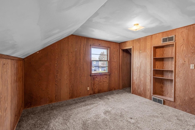 bonus room with wooden walls, vaulted ceiling, carpet flooring, and visible vents