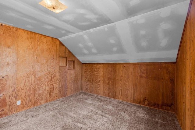 bonus room featuring carpet floors, wood walls, and lofted ceiling