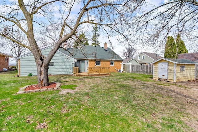 back of property with fence, brick siding, a storage shed, a wooden deck, and an outbuilding
