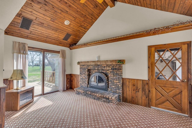 unfurnished living room featuring high vaulted ceiling, wood walls, carpet, a wainscoted wall, and visible vents