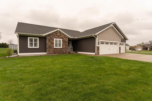 351 Alyssa St, Tomah, WI 54660 - view of front of home with a front yard, stone siding, a shingled roof, concrete driveway, and an attached garage