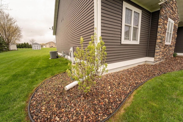 351 Alyssa St, Tomah, WI 54660 - view of home's exterior with a storage shed, a lawn, an outbuilding, central AC, and stone siding