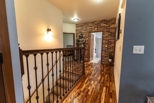 351 Alyssa St, Tomah, WI 54660 - corridor featuring wood finished floors, brick wall, and an upstairs landing