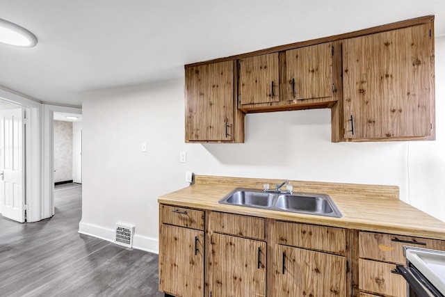 kitchen featuring visible vents, baseboards, dark wood-style floors, light countertops, and a sink