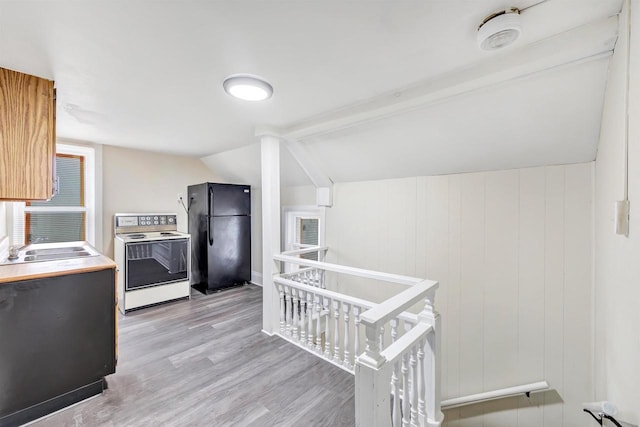 kitchen with electric range, a sink, freestanding refrigerator, light wood-type flooring, and vaulted ceiling