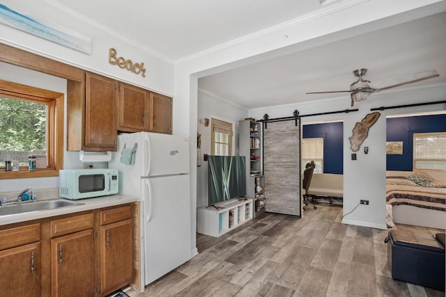 416 Waldeck Dr, Twin Lakes, WI 53181 - kitchen with crown molding, brown cabinetry, white appliances, a barn door, and light countertops