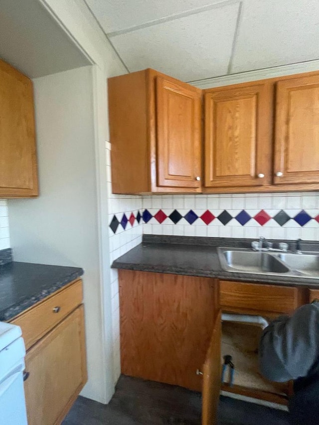 kitchen featuring a sink, brown cabinets, dark countertops, and tasteful backsplash
