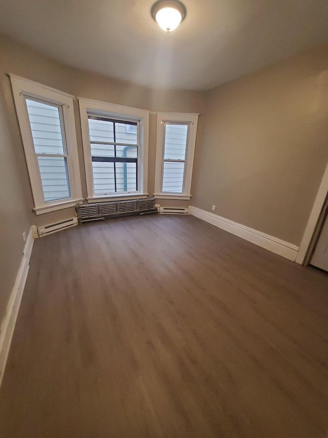 empty room with baseboards, dark wood-style floors, and a baseboard radiator
