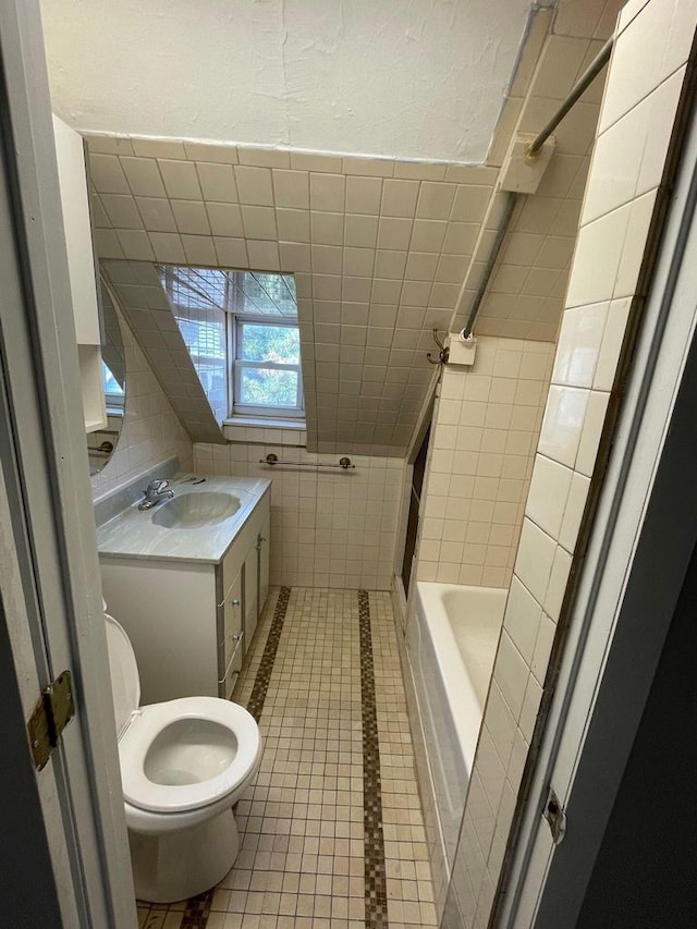 bathroom with toilet, tile patterned floors, tile walls, and vanity