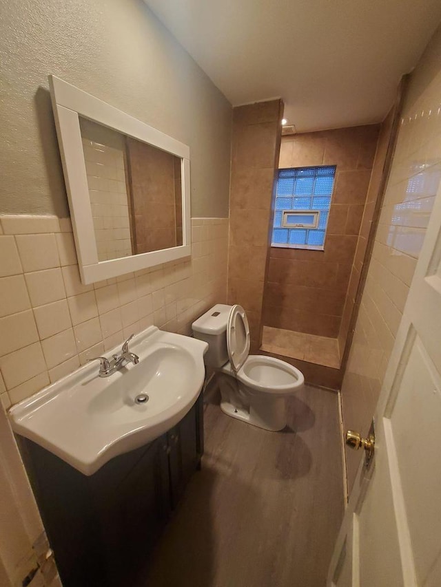 full bathroom featuring tile walls, a shower stall, wood finished floors, vanity, and toilet