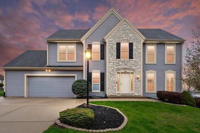 view of front facade with a lawn, driveway, and stone siding