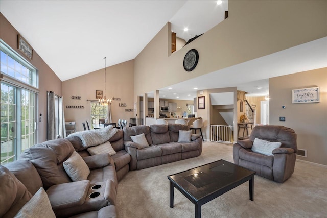 living room with light colored carpet, high vaulted ceiling, an inviting chandelier, and visible vents
