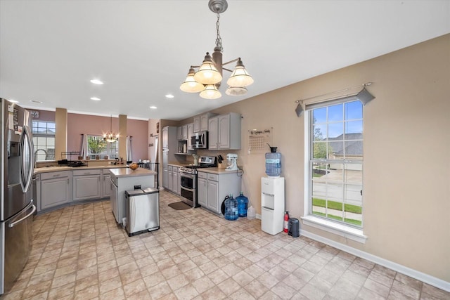 kitchen featuring appliances with stainless steel finishes, light countertops, a chandelier, baseboards, and gray cabinetry
