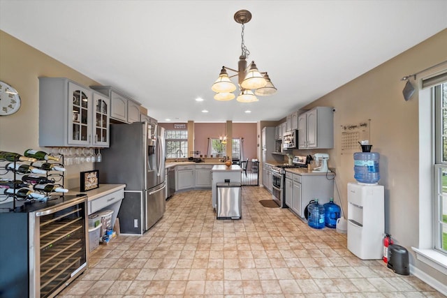 kitchen featuring wine cooler, glass insert cabinets, gray cabinets, a notable chandelier, and stainless steel appliances