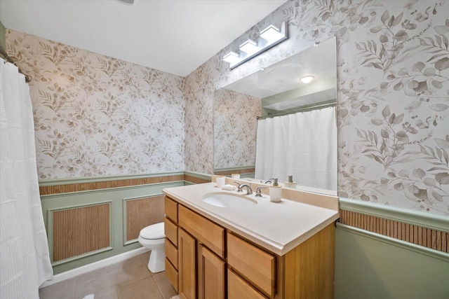 bathroom with tile patterned flooring, a wainscoted wall, toilet, and wallpapered walls
