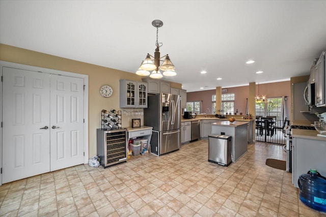 kitchen featuring stainless steel appliances, gray cabinetry, a notable chandelier, and beverage cooler
