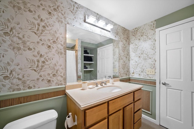 full bath featuring vanity, wainscoting, wallpapered walls, and toilet