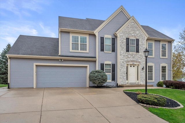 view of front facade with a front yard, stone siding, and concrete driveway