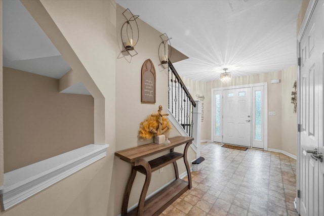 entryway with stairway, baseboards, and stone finish flooring