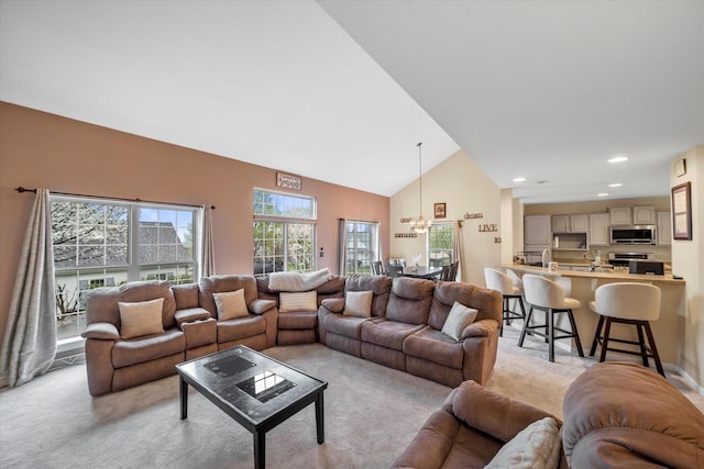 living area with an inviting chandelier, recessed lighting, high vaulted ceiling, and light colored carpet